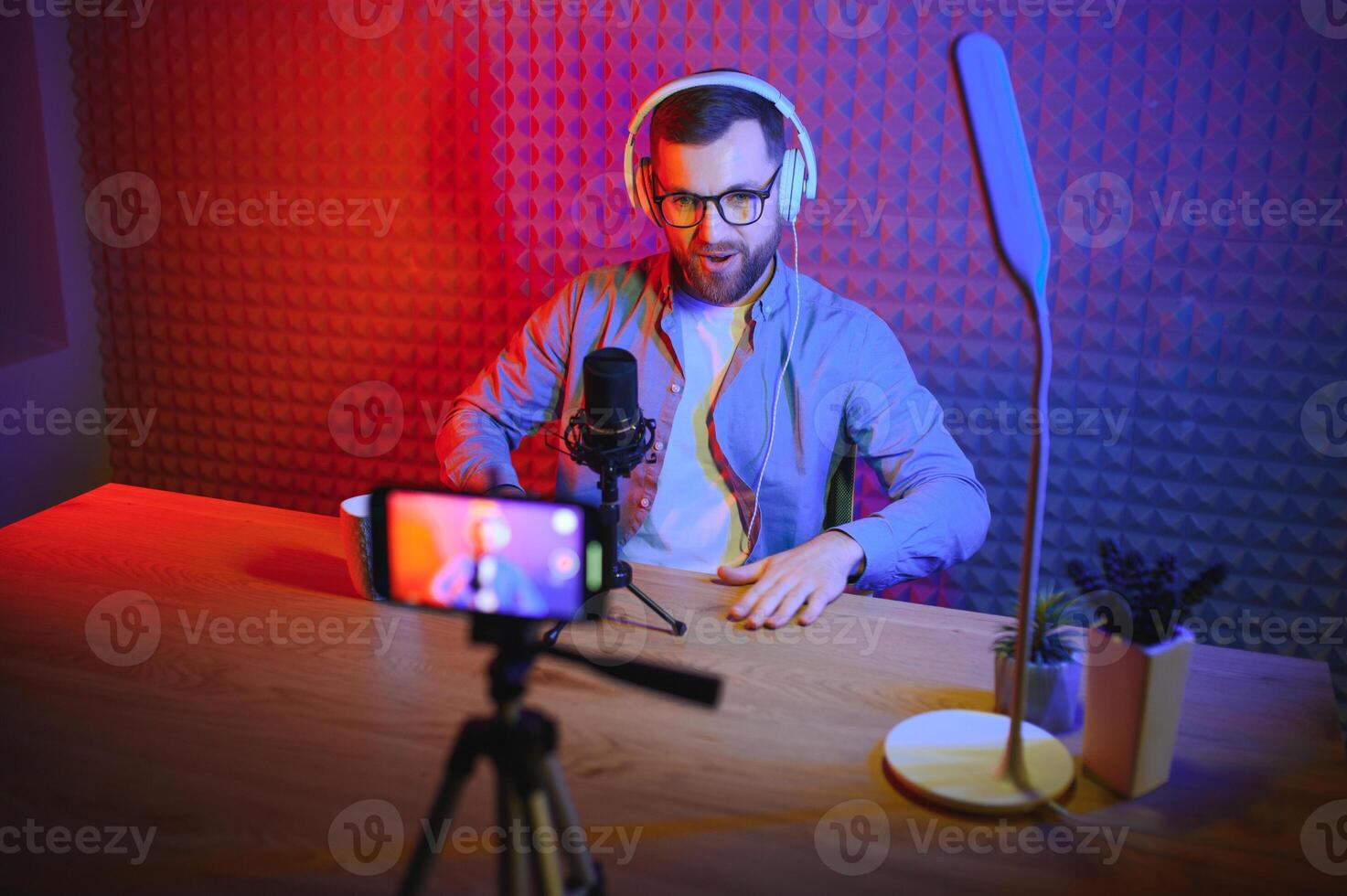 Young man recording or streaming podcast using microphone at his small broadcast studio. Content creator. photo