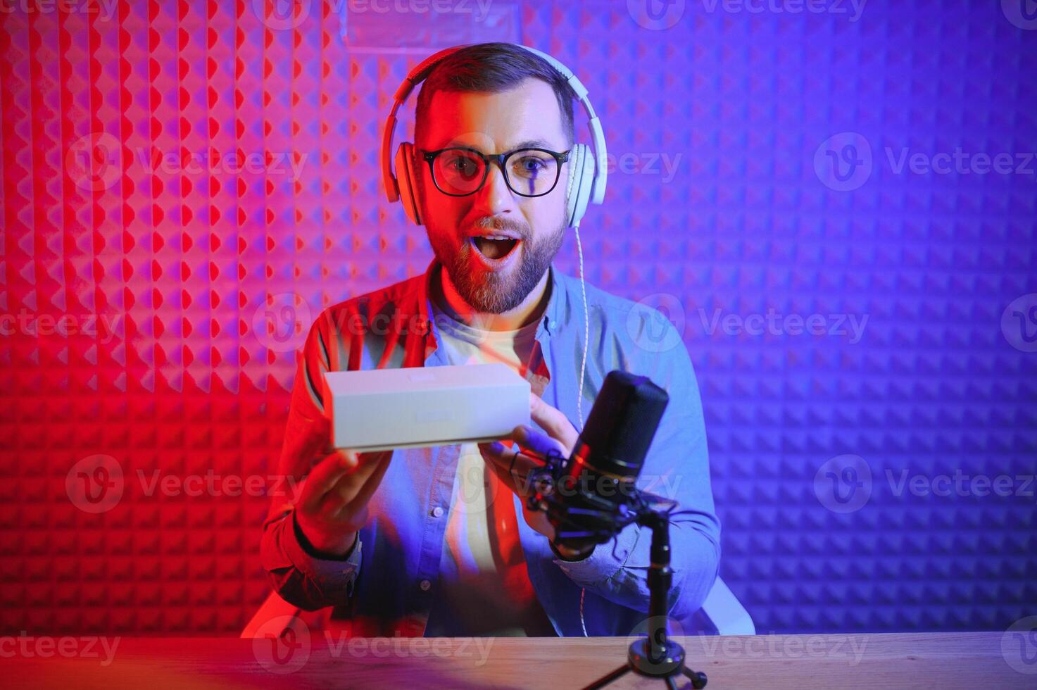 Male technology blogger recording blog or vlog review of new smartphone, showing it on camera at home studio. Blogging, Work from Home concept. Selective focus. Web Banner photo