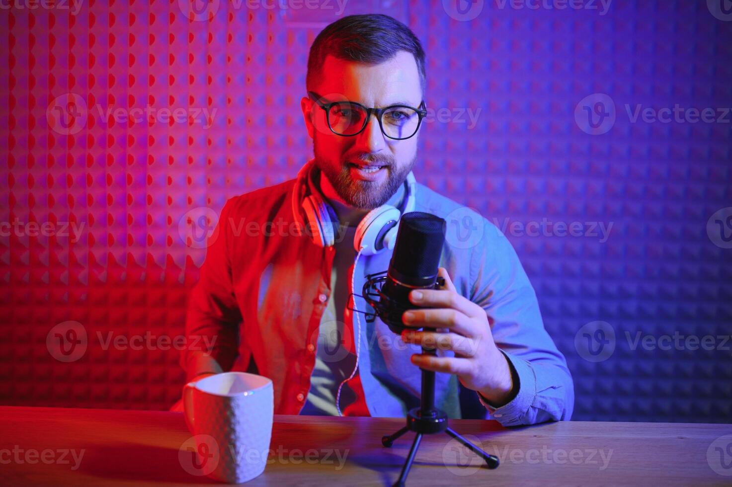Young man recording or streaming podcast using microphone at his small broadcast studio. Content creator. photo