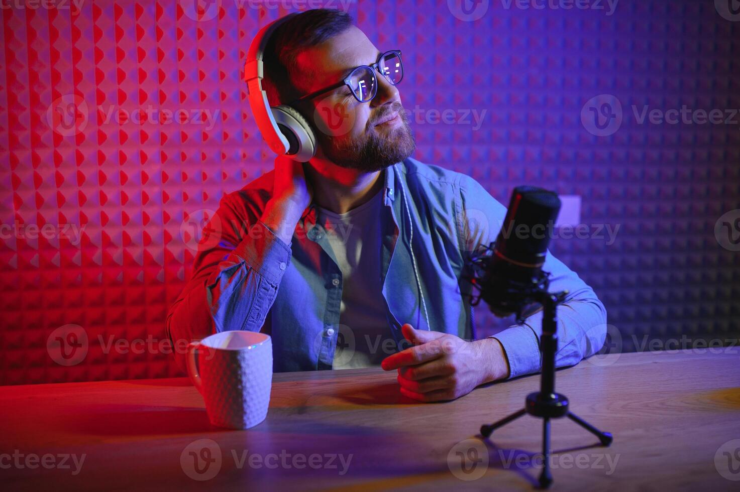 Young man recording or streaming podcast using microphone at his small broadcast studio. Content creator. photo