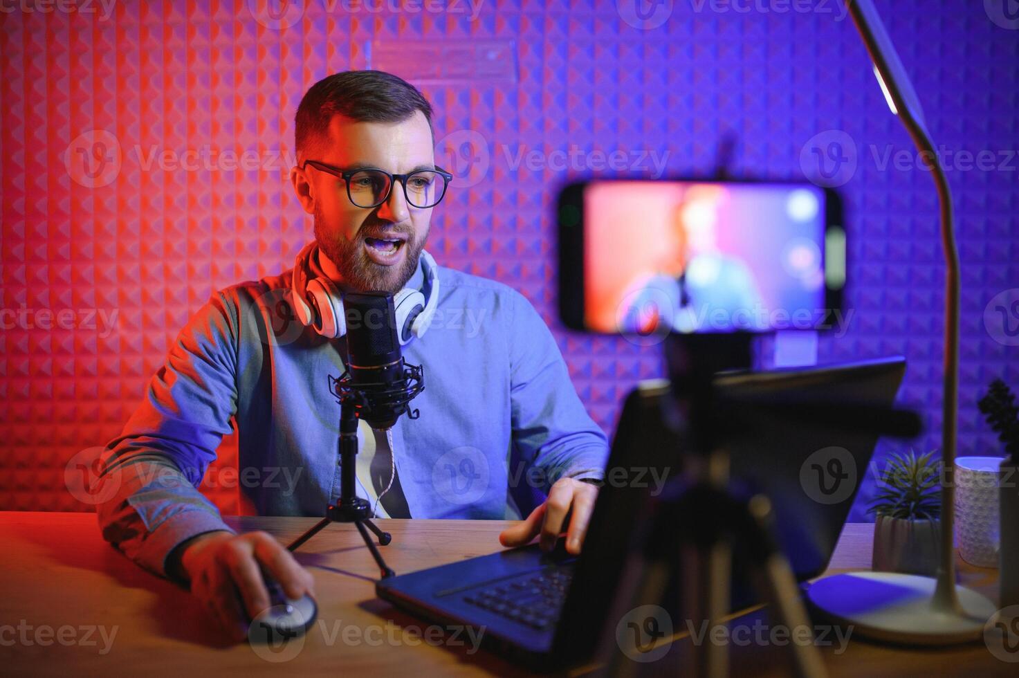Young man recording or streaming podcast using microphone at his small broadcast studio. Content creator. photo