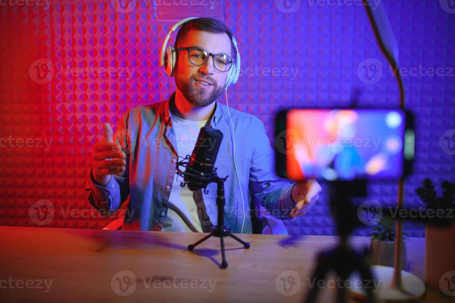 Young man recording or streaming podcast using microphone at his small broadcast studio. Content creator. photo
