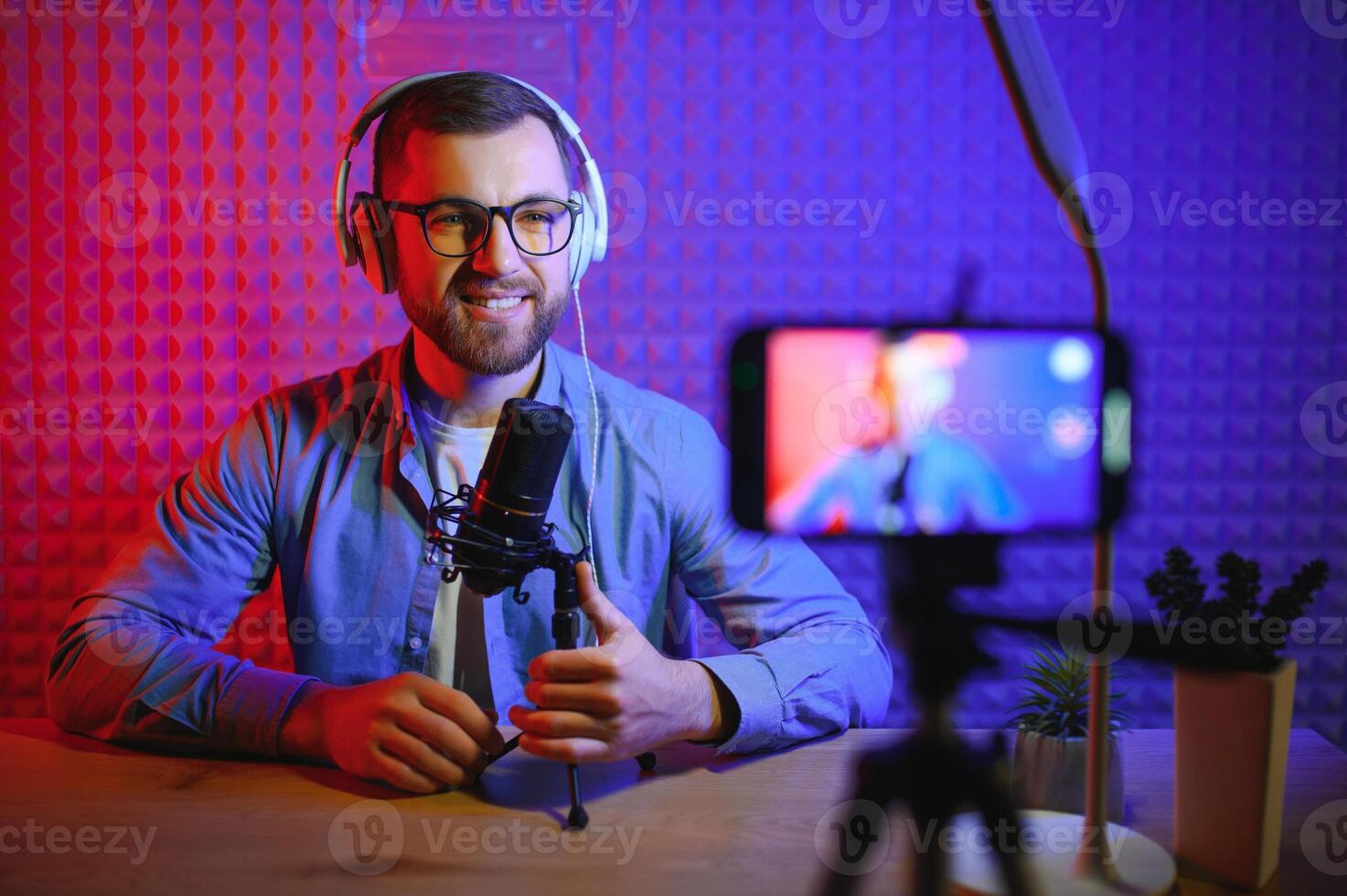 Young man recording or streaming podcast using microphone at his small broadcast studio. Content creator. photo