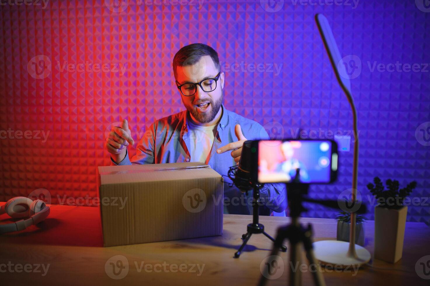 Young man recording or streaming podcast using microphone at his small broadcast studio. Content creator. photo