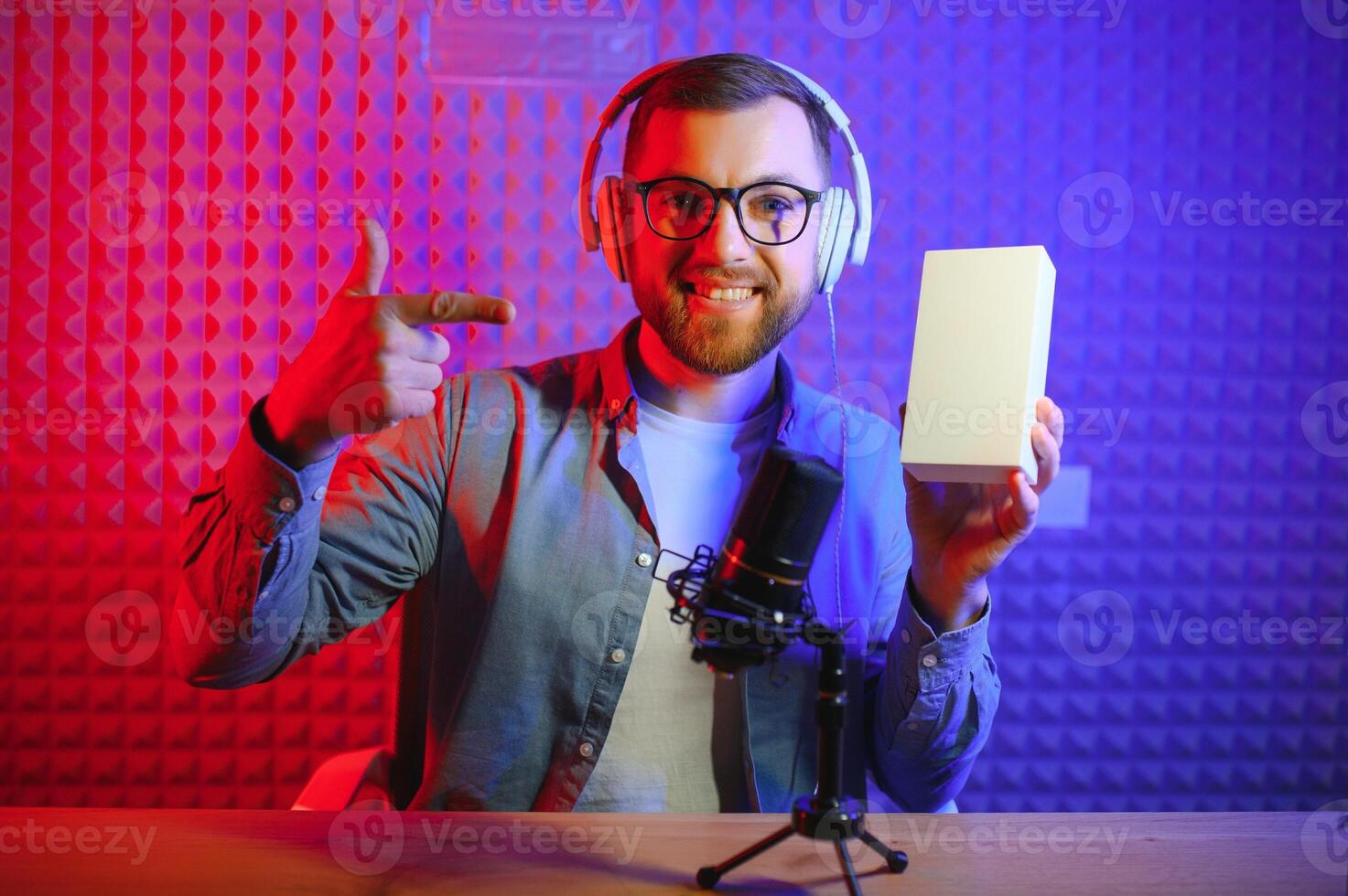 Male technology blogger recording blog or vlog review of new smartphone, showing it on camera at home studio. Blogging, Work from Home concept. Selective focus. Web Banner photo