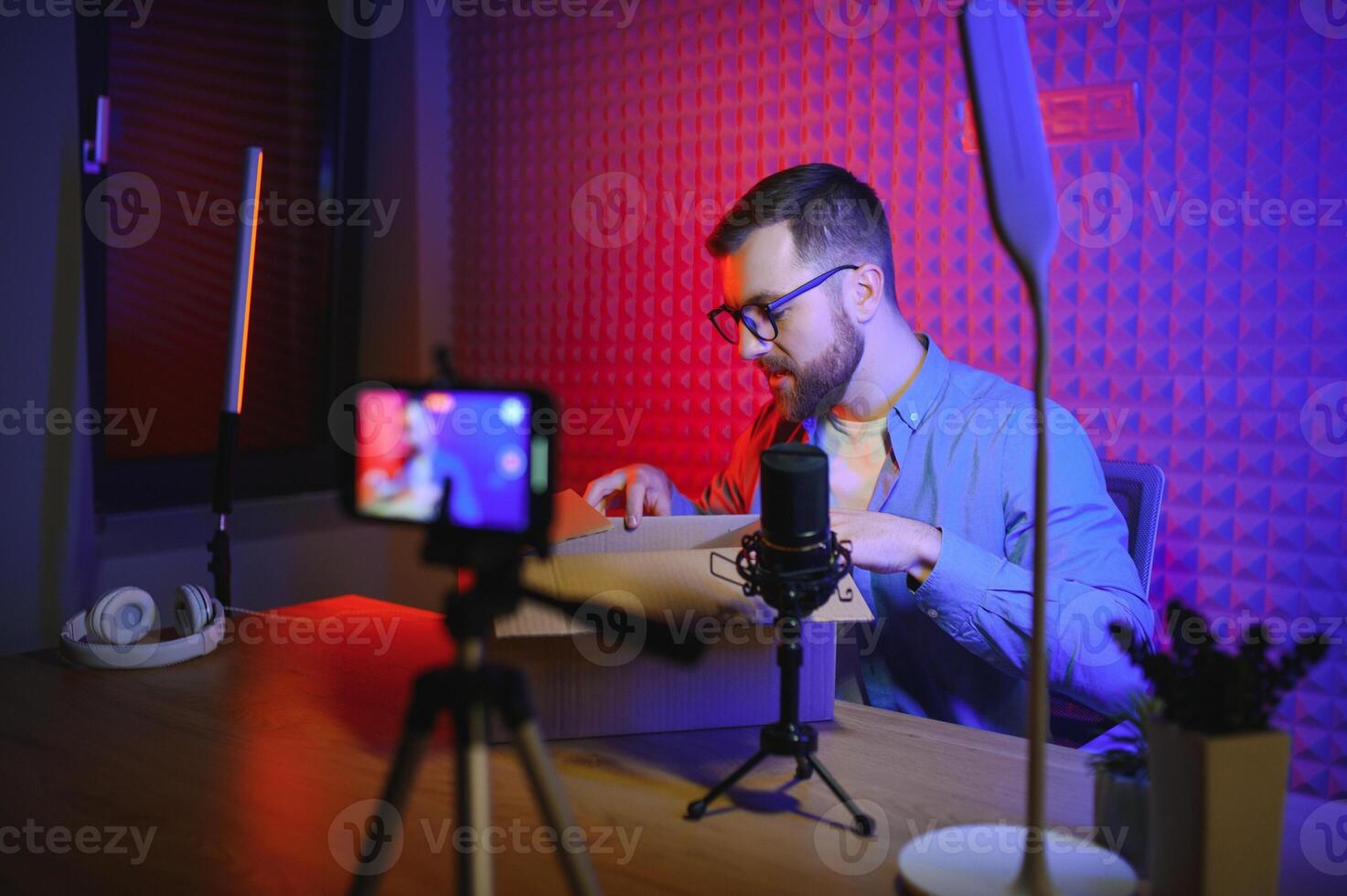 Joyful young man recording unboxing in studio photo