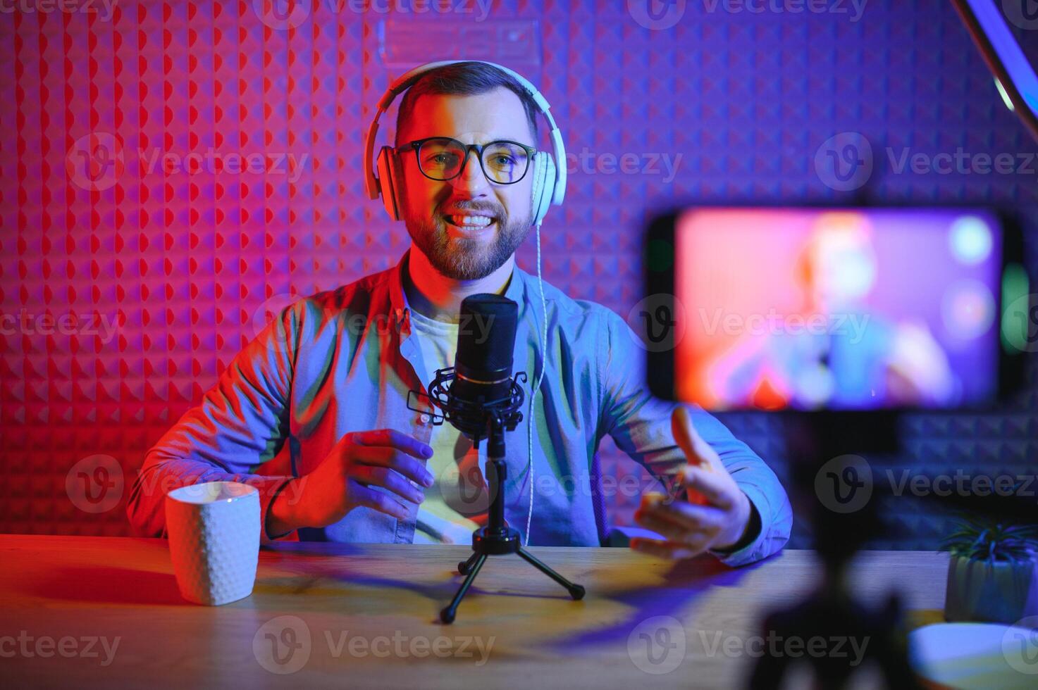 Young man recording or streaming podcast using microphone at his small broadcast studio. Content creator. photo