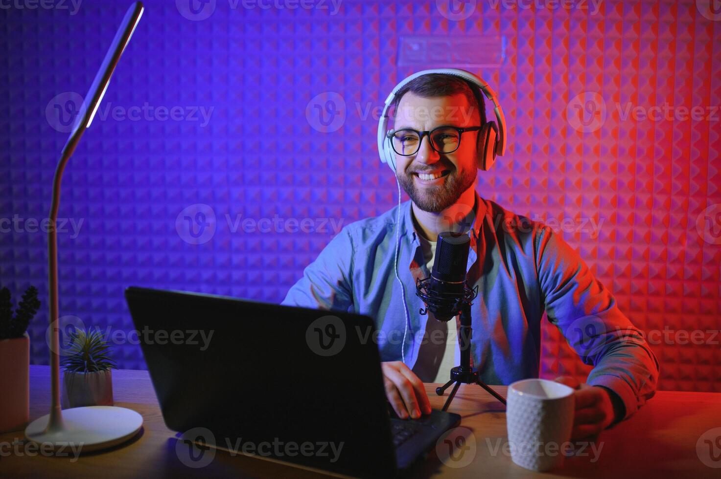 Young man recording or streaming podcast using microphone at his small broadcast studio. Content creator. photo