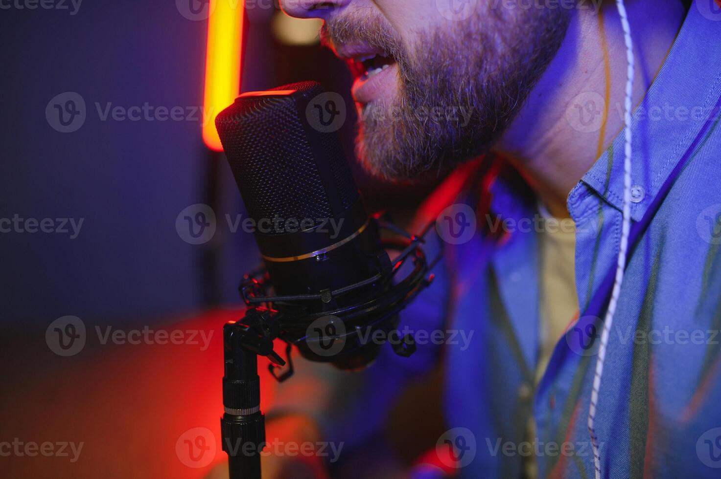 Young man recording or streaming podcast using microphone at his small broadcast studio. Content creator. photo