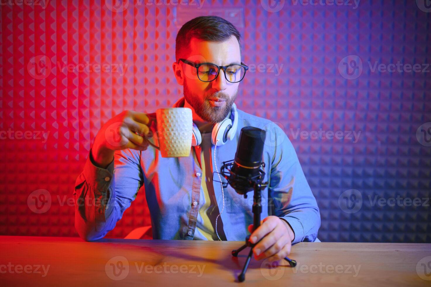 Young man recording or streaming podcast using microphone at his small broadcast studio. Content creator. photo