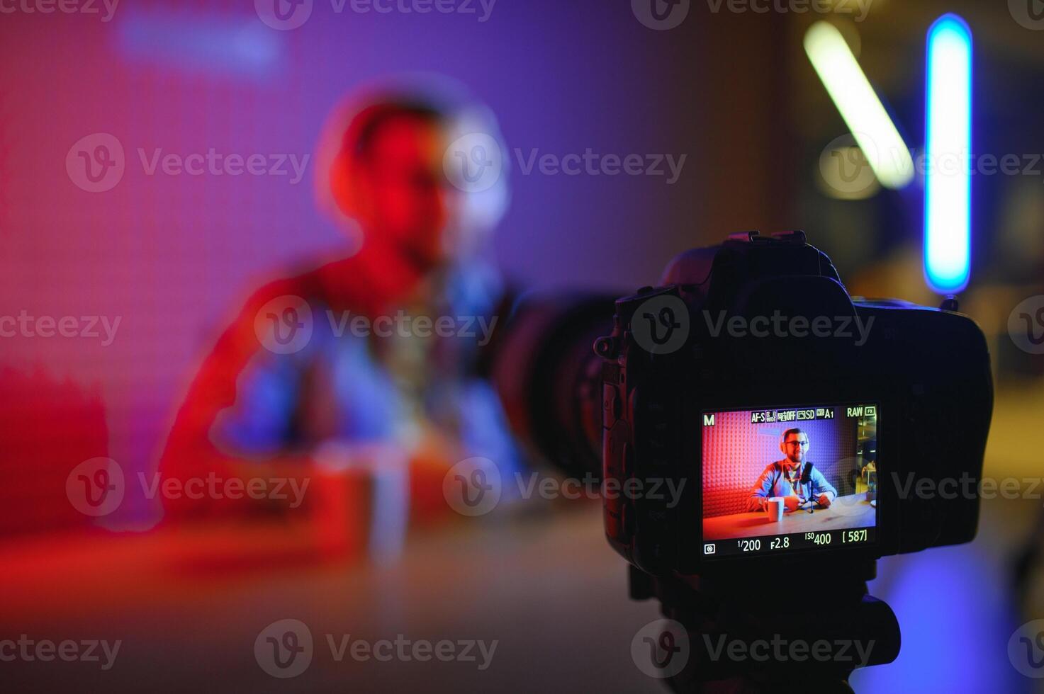 Young man recording or streaming podcast using microphone at his small broadcast studio. Content creator. photo