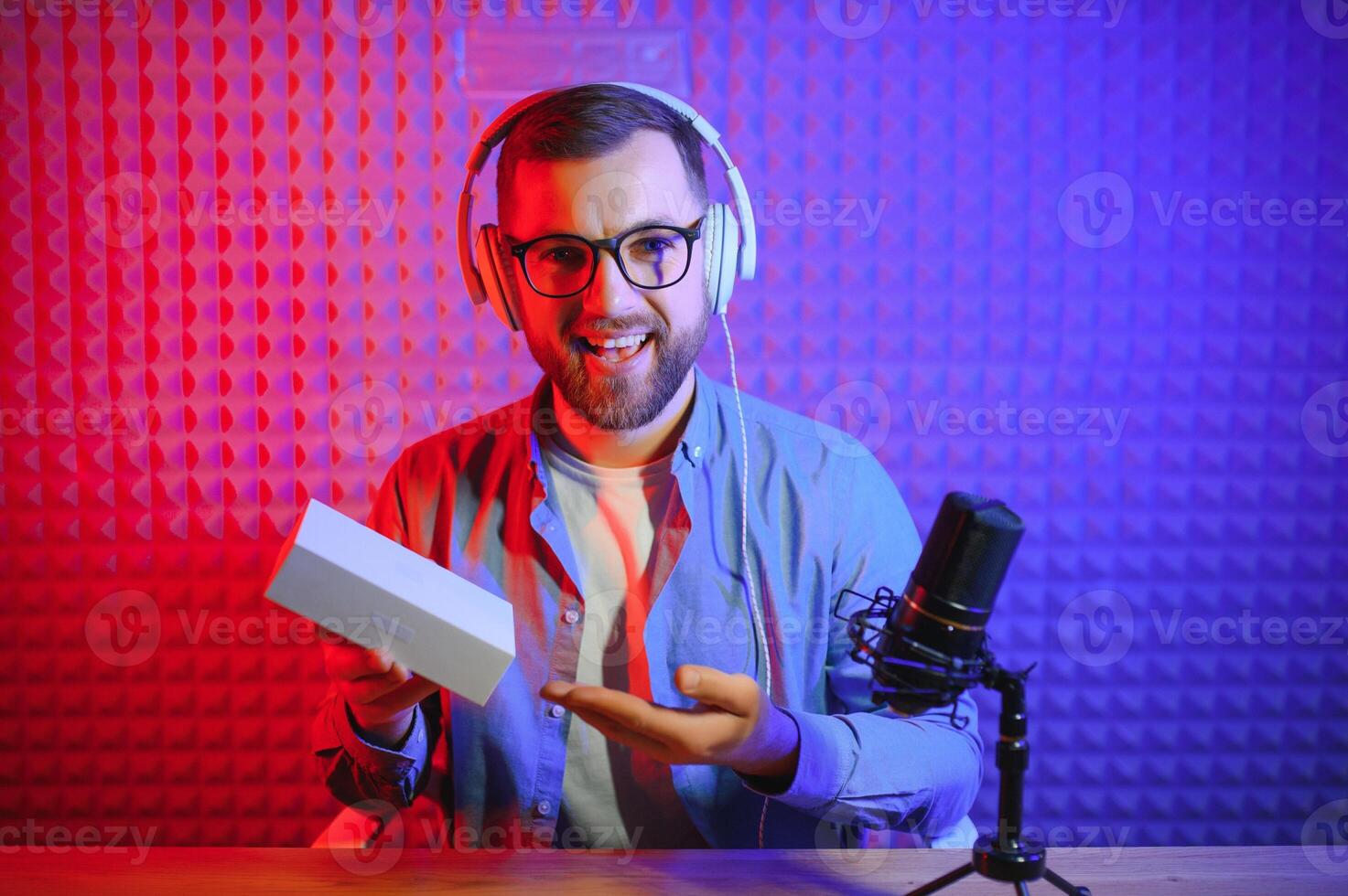 Male technology blogger recording blog or vlog review of new smartphone, showing it on camera at home studio. Blogging, Work from Home concept. Selective focus. Web Banner photo