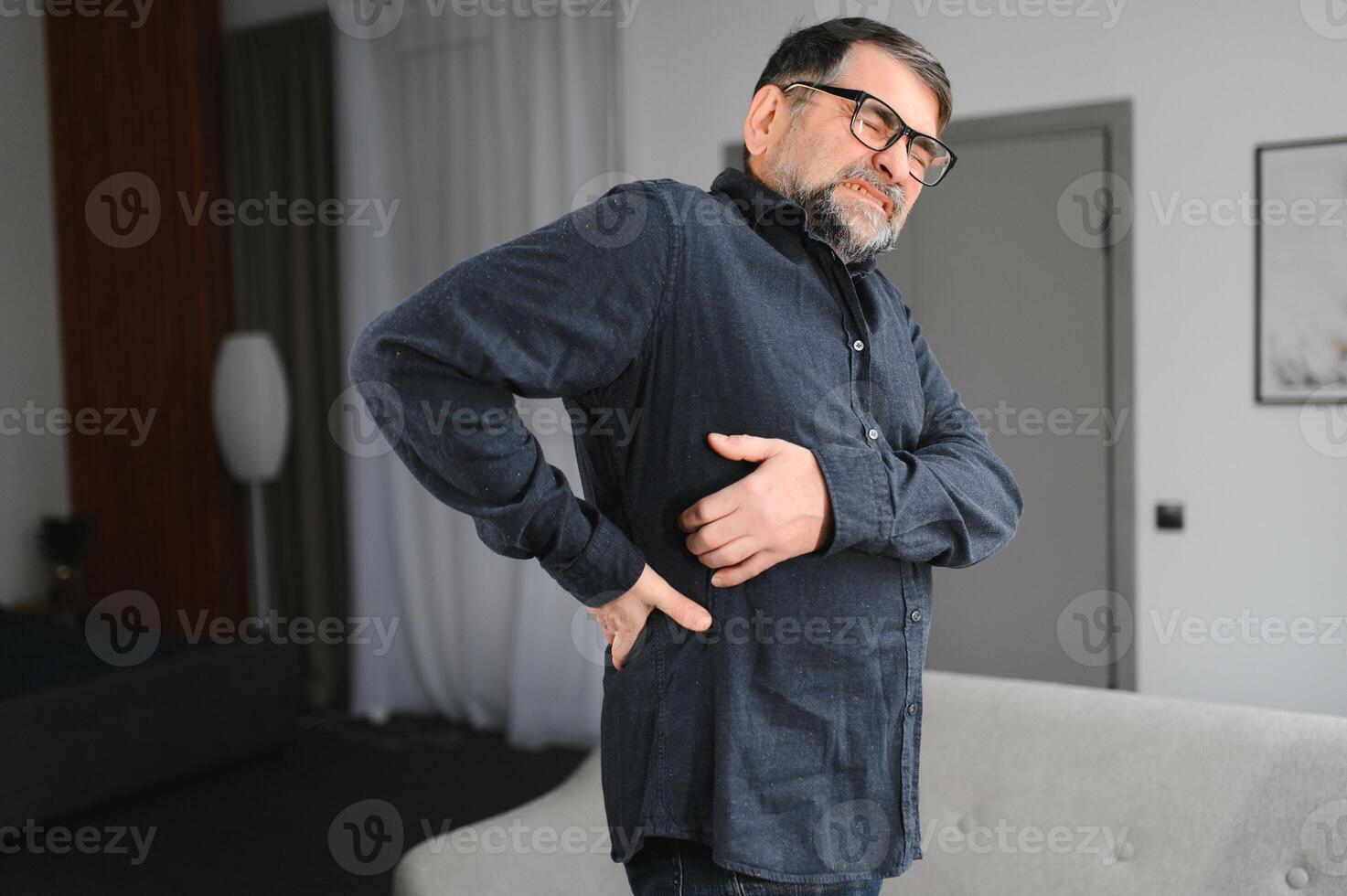Senior man is suffering from pain in lower back at home photo