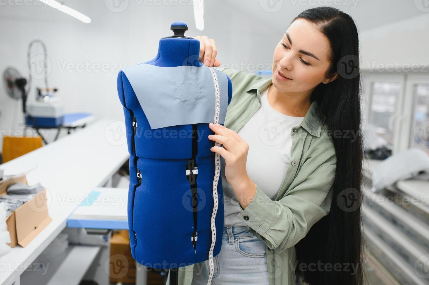 Happy female dressmaker working with sewing machine at textile factory. photo