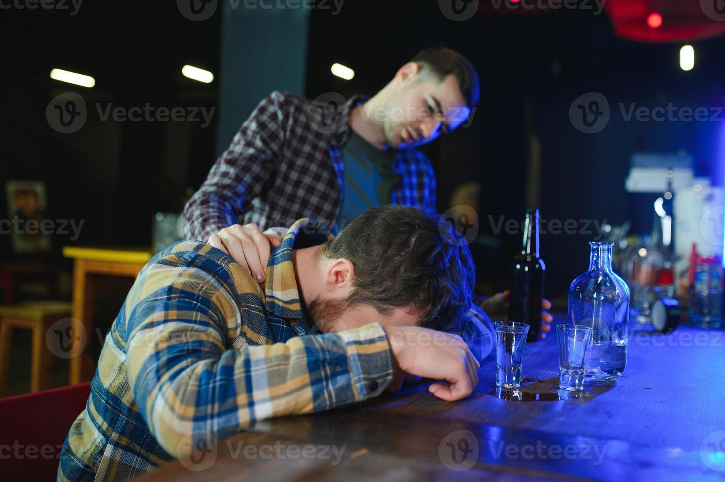 Sad young man sitting at bar counter in pub. Upset man drinks alcohol because of problems at work. photo