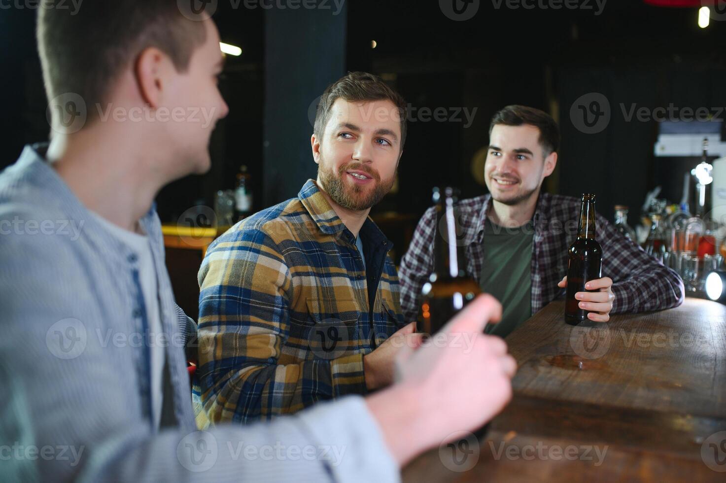 Friends resting in the pub with beer in hands. Having conversation. photo