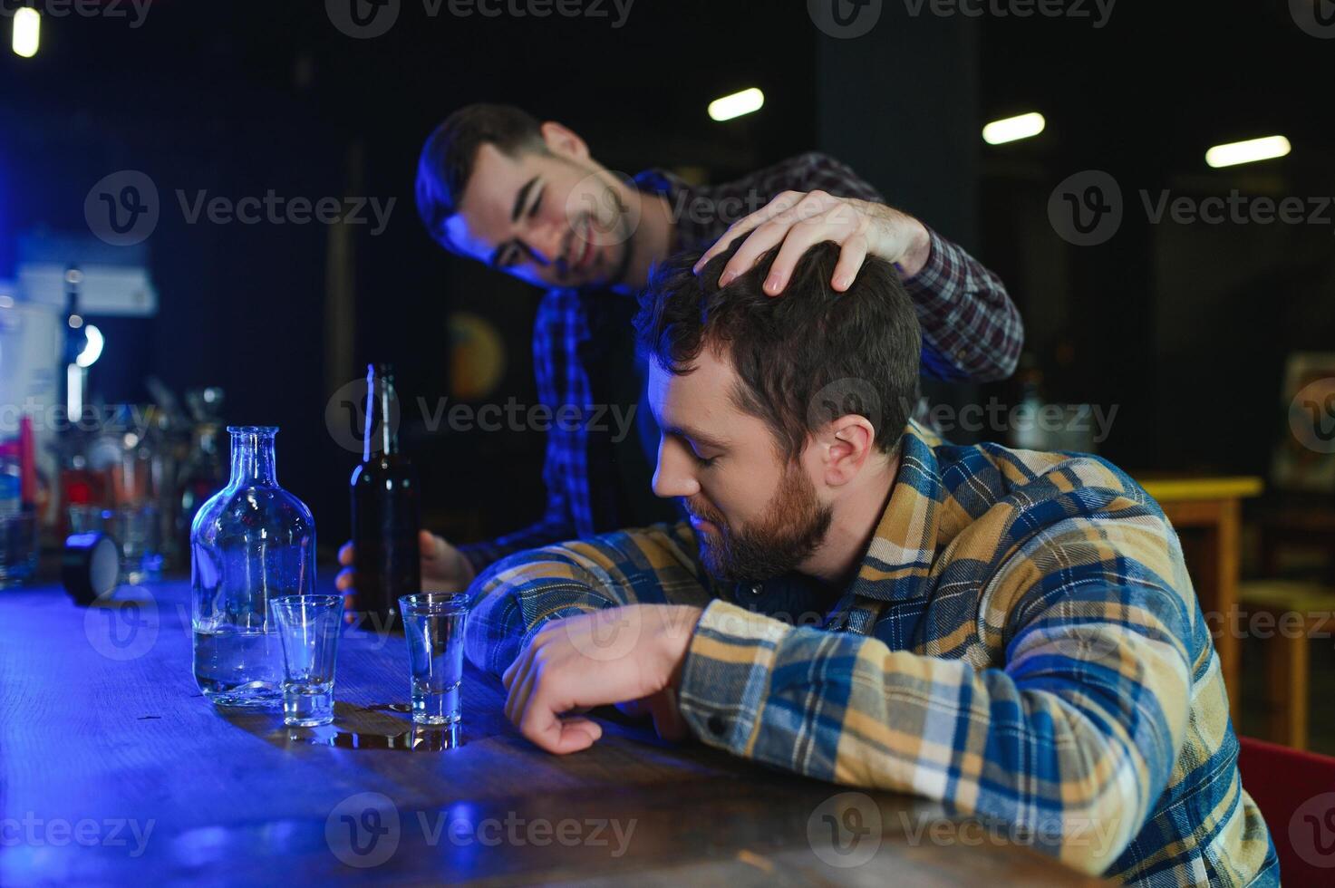 Sad young man sitting at bar counter in pub. Upset man drinks alcohol because of problems at work. photo