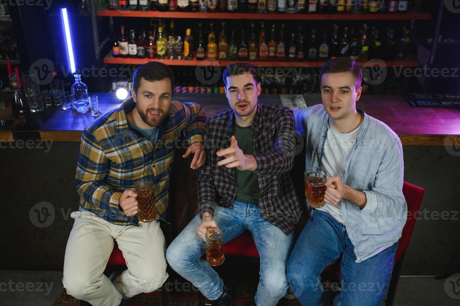 Soccer fans at the bar. Happy football fans cheering at bar and drinking beer while bartender serving beer at the background photo