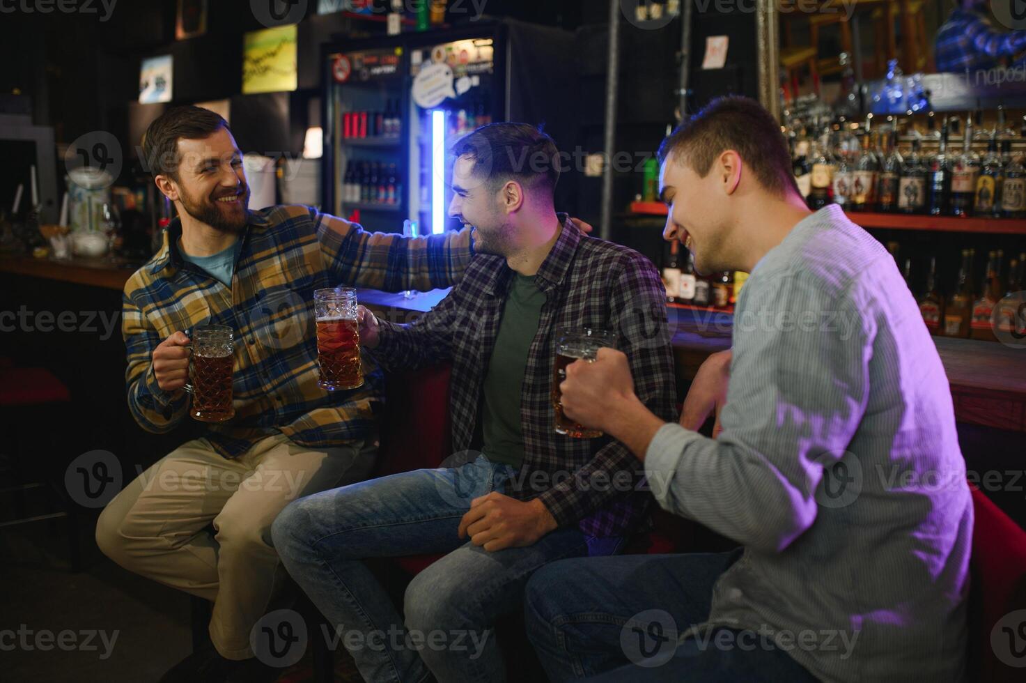 Friends resting in the pub with beer in hands. Having conversation. photo