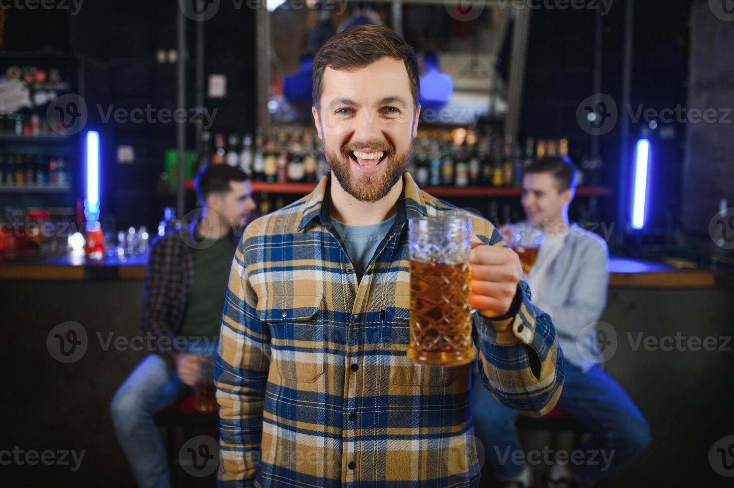 Night in bar. Portrait of cheerful men drinking beer at the bar photo