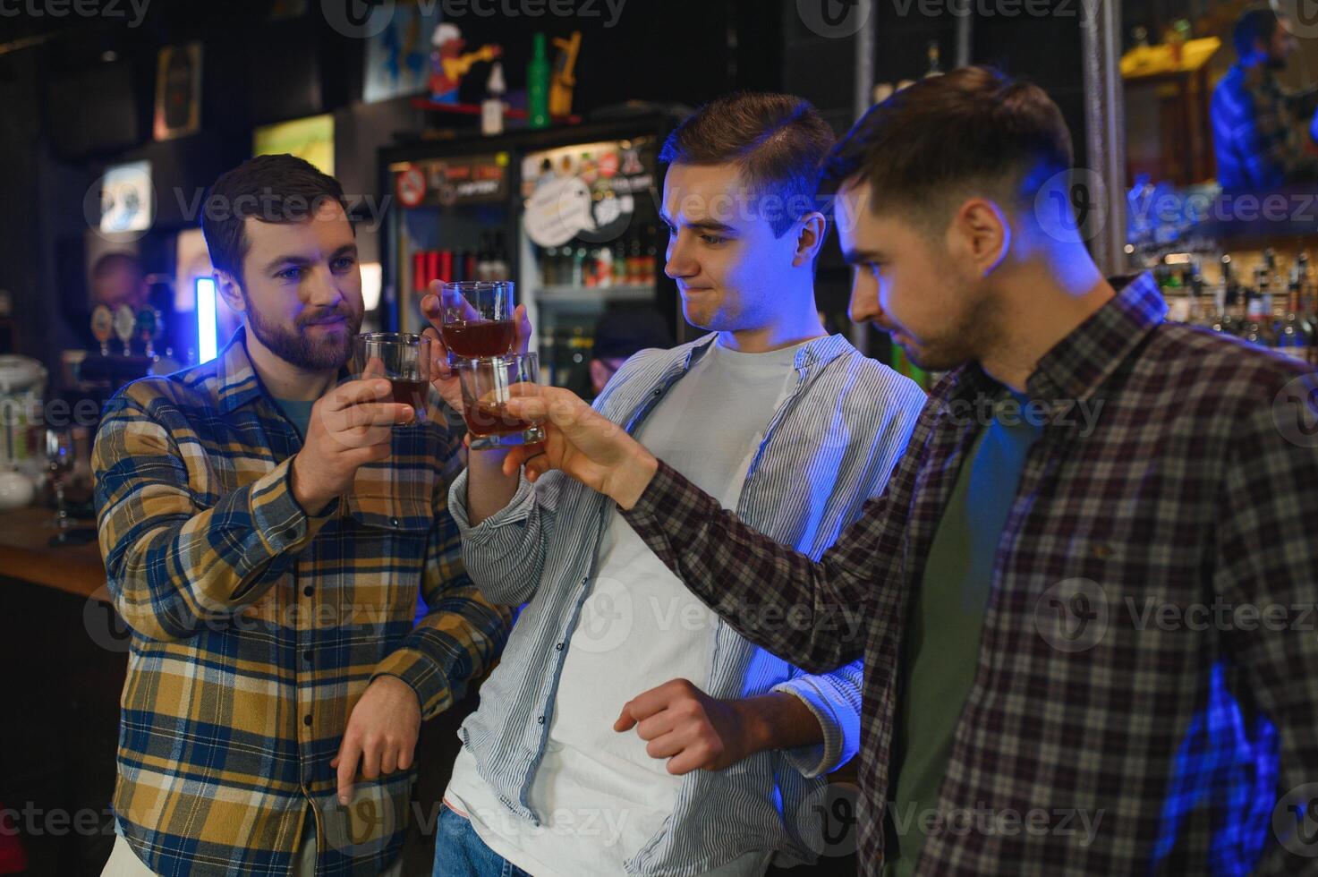 male friends spending time together in bar and having fun. Bearded men smiling, looking at each other and communicating. Men holding crystal glasses of whisky or scotch. photo