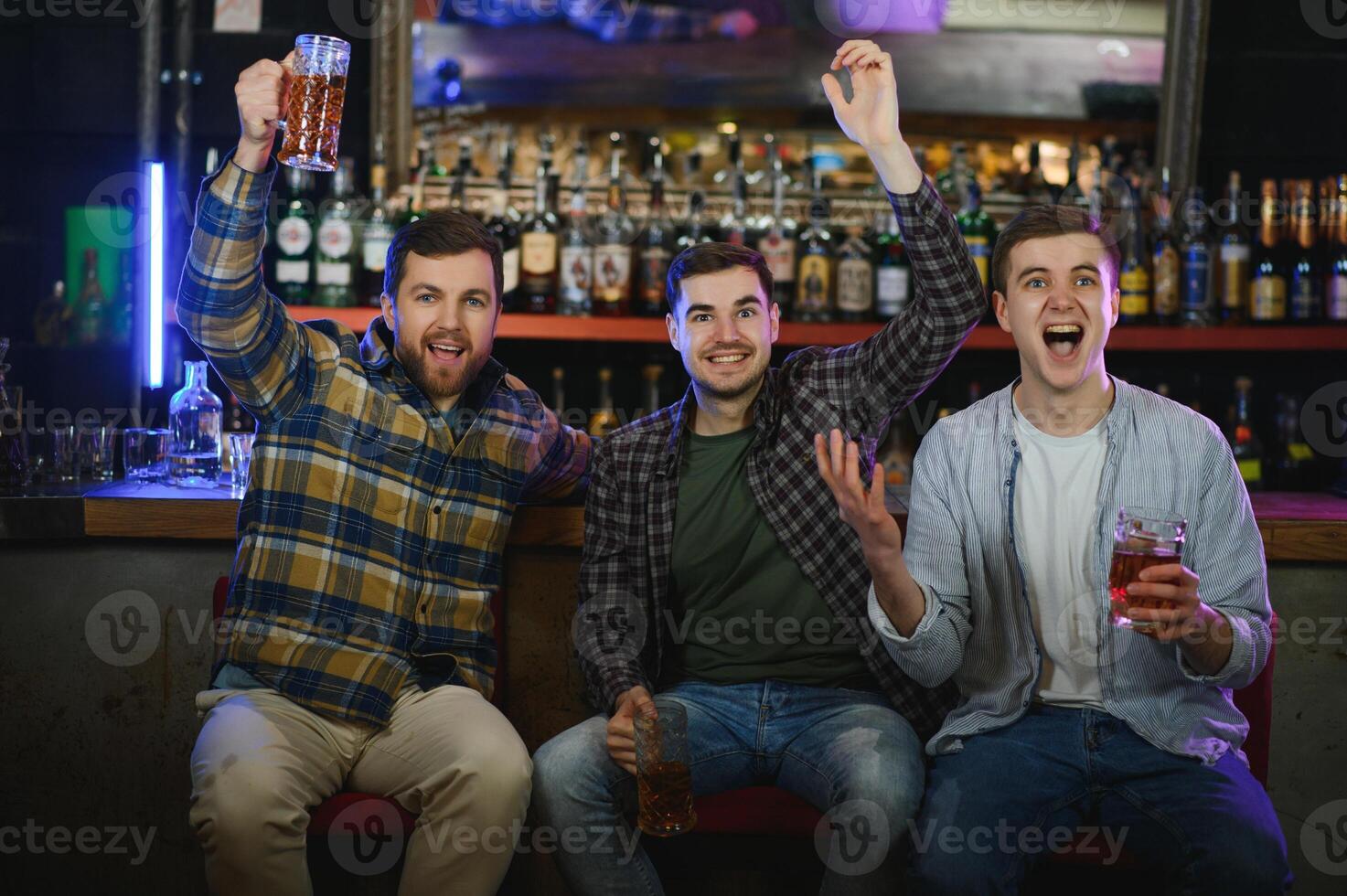 Soccer fans at the bar. Happy football fans cheering at bar and drinking beer while bartender serving beer at the background photo