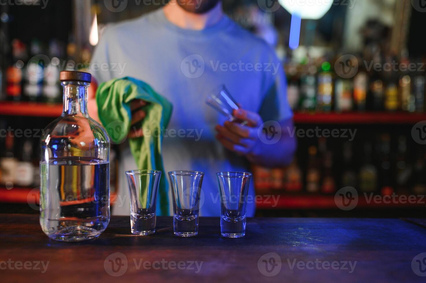 Barman pouring hard spirit into glasses for two male friends relaxing in a bar photo