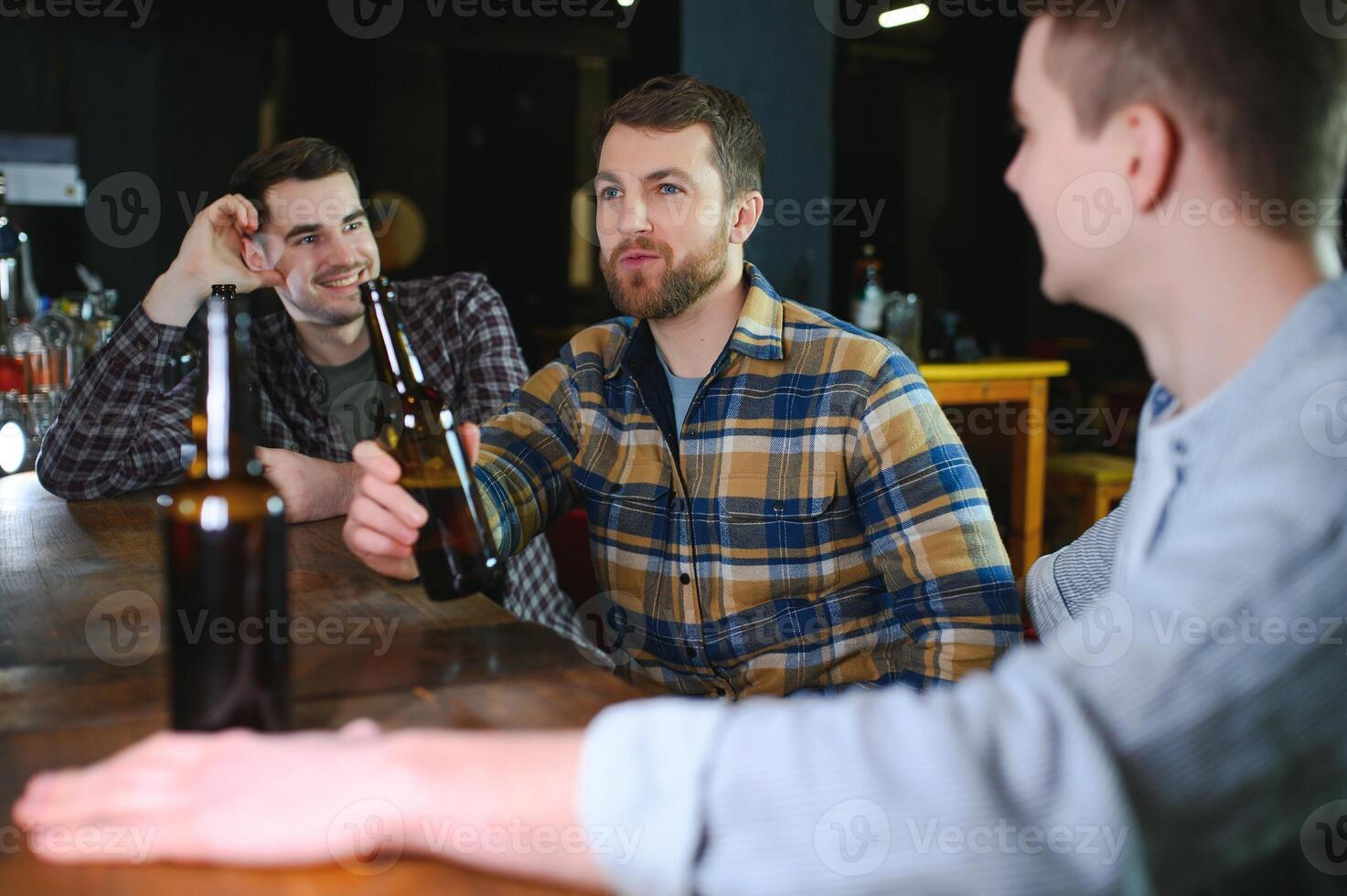 Friends having fun. Happy young men in casual wear drinking beer in pub. photo