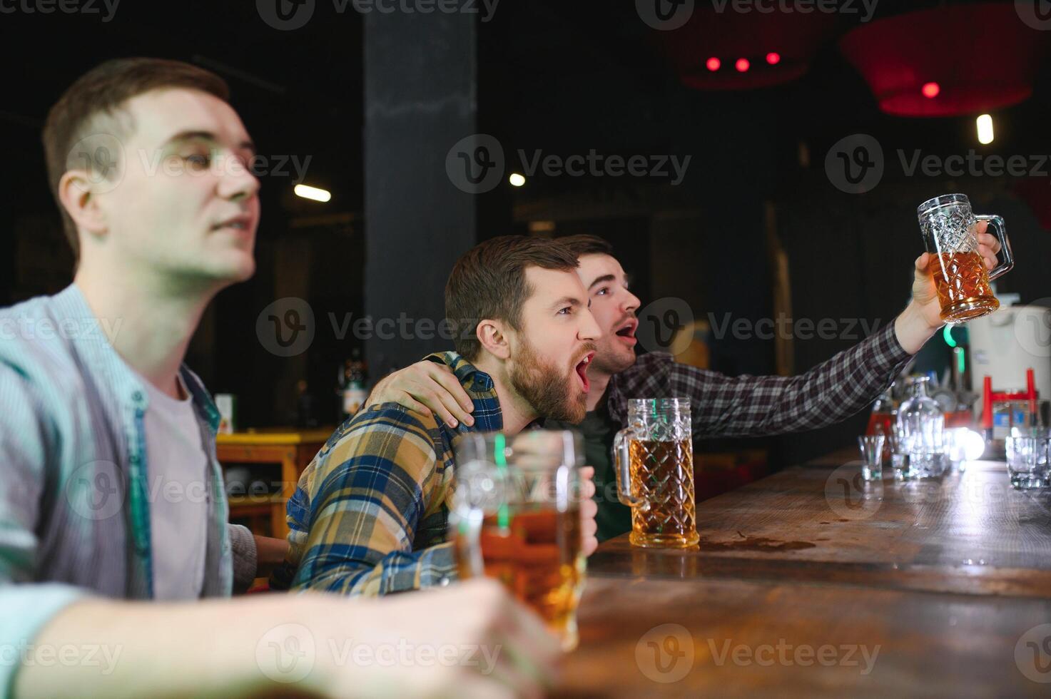 Soccer fans at the bar. Happy football fans cheering at bar and drinking beer while bartender serving beer at the background photo