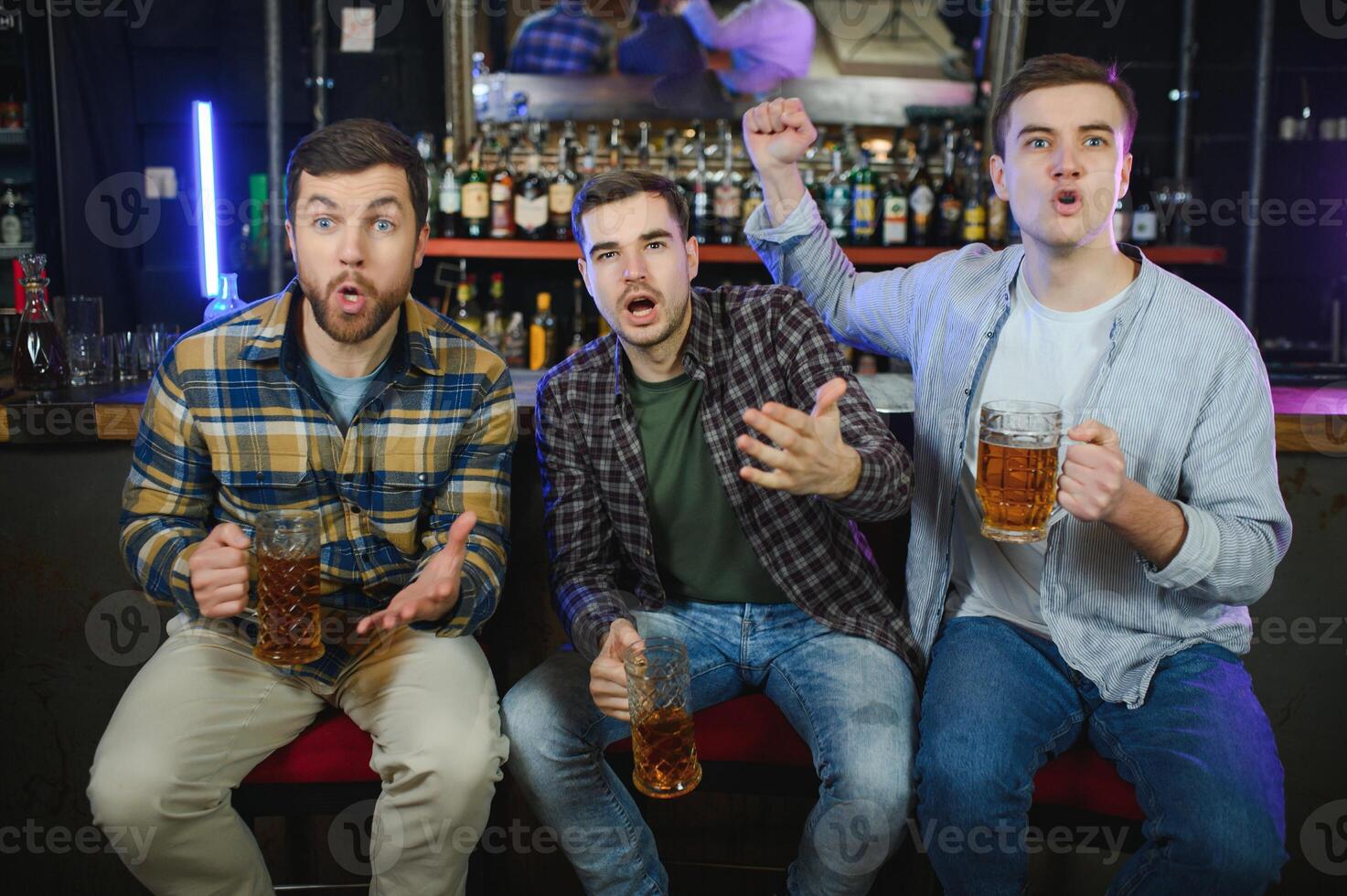Soccer fans at the bar. Happy football fans cheering at bar and drinking beer while bartender serving beer at the background photo