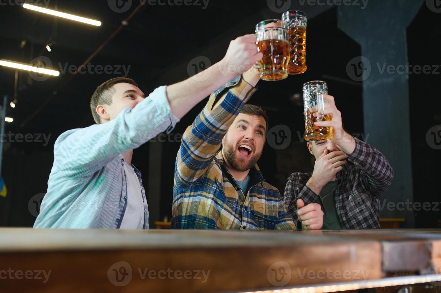 Soccer fans at the bar. Happy football fans cheering at bar and drinking beer while bartender serving beer at the background photo