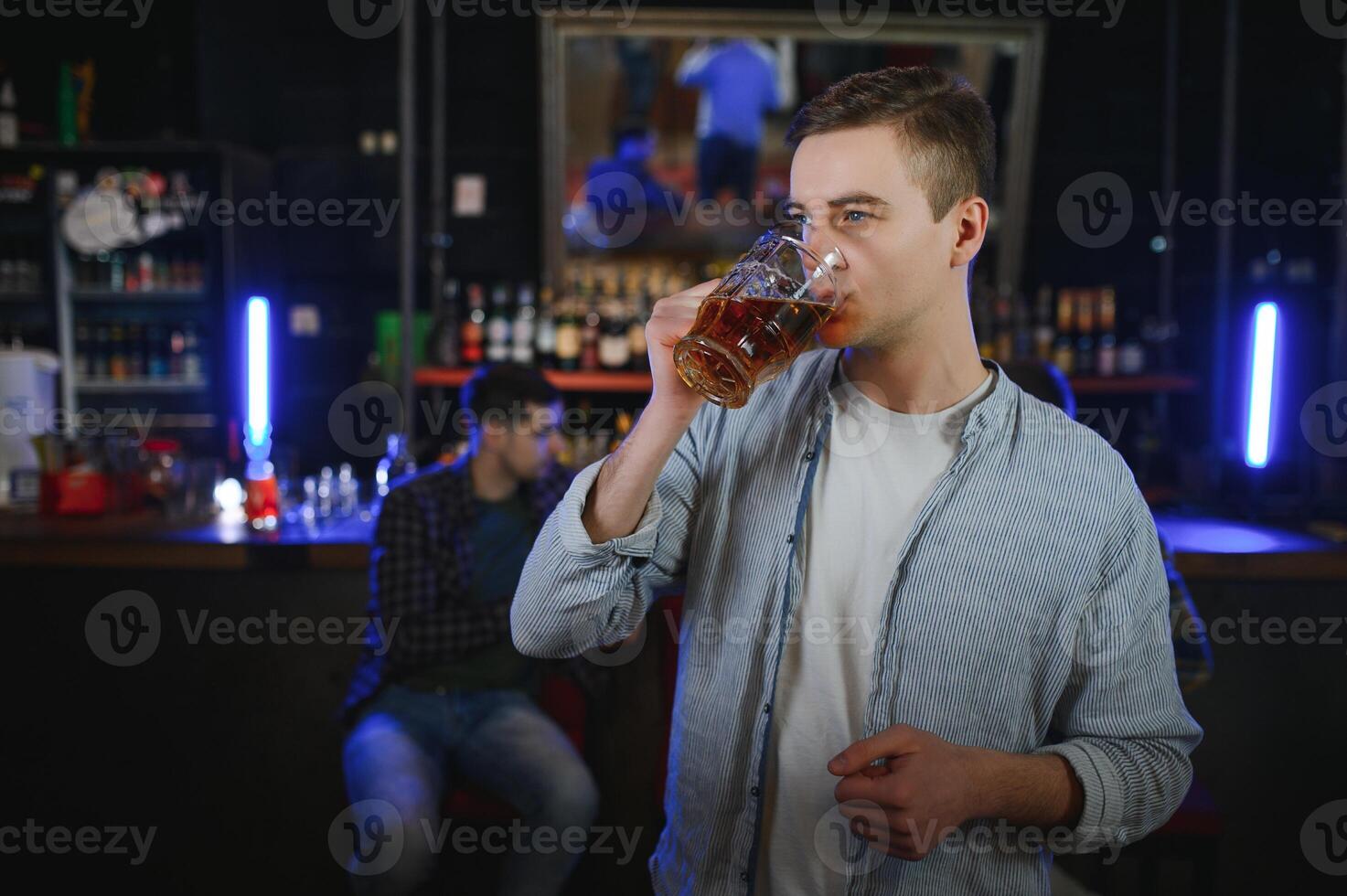 Night in bar. Portrait of cheerful men drinking beer at the bar photo