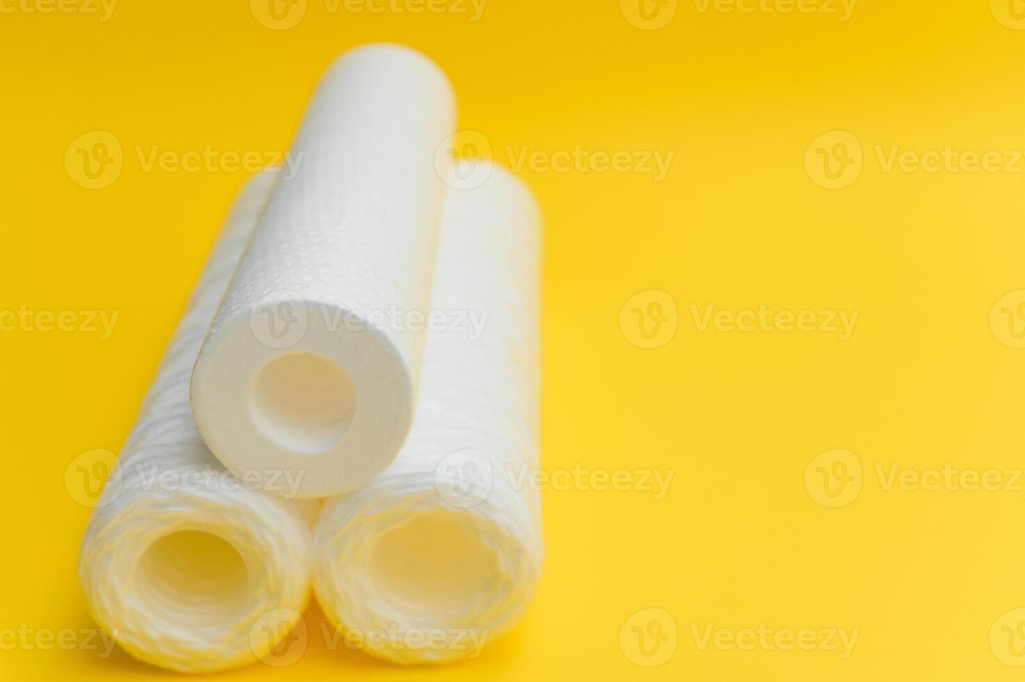 Water filters. Carbon cartridges and a glass on a yellow background. Household filtration system photo