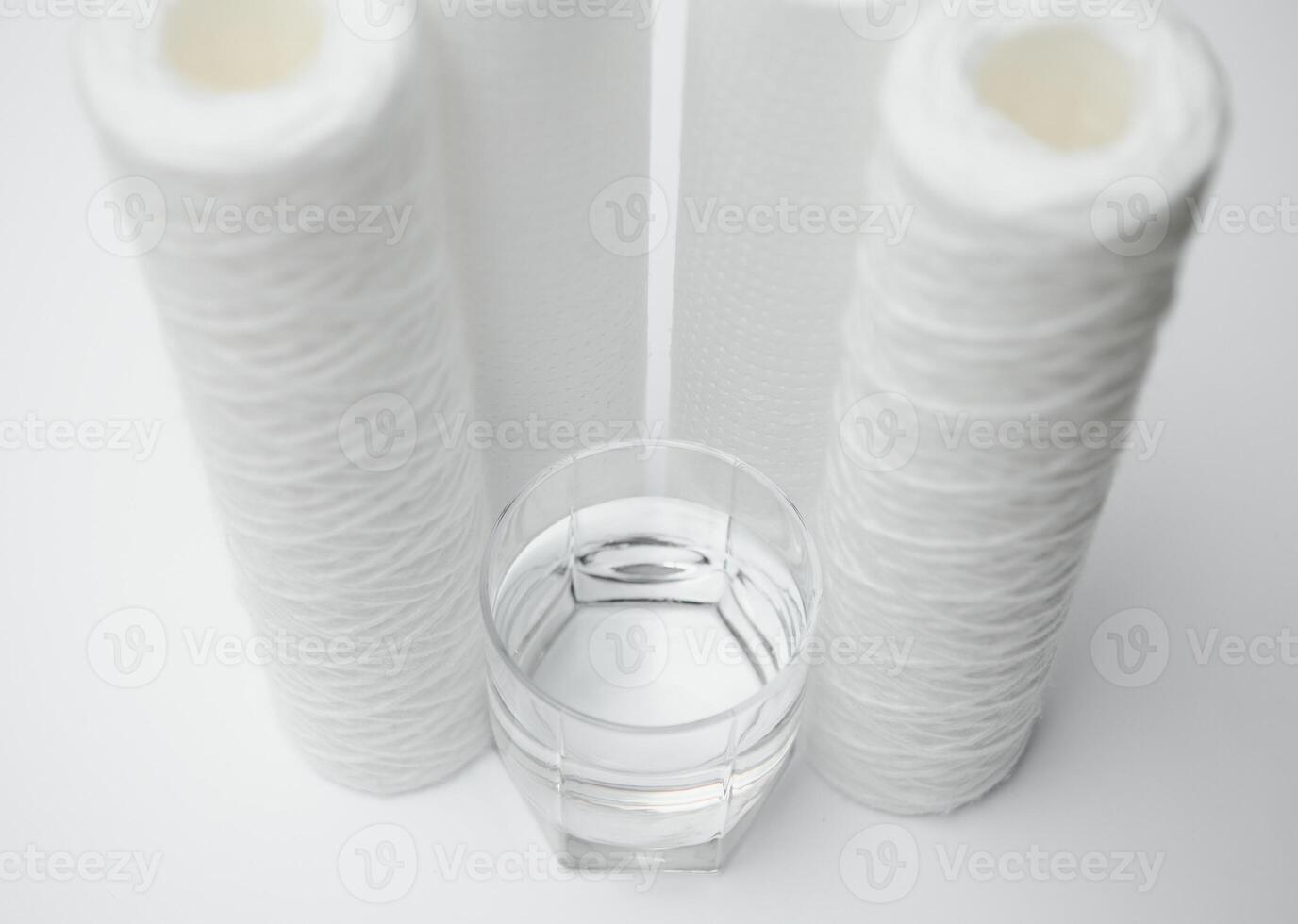 A glass of drink water and filter cartridges at white background photo