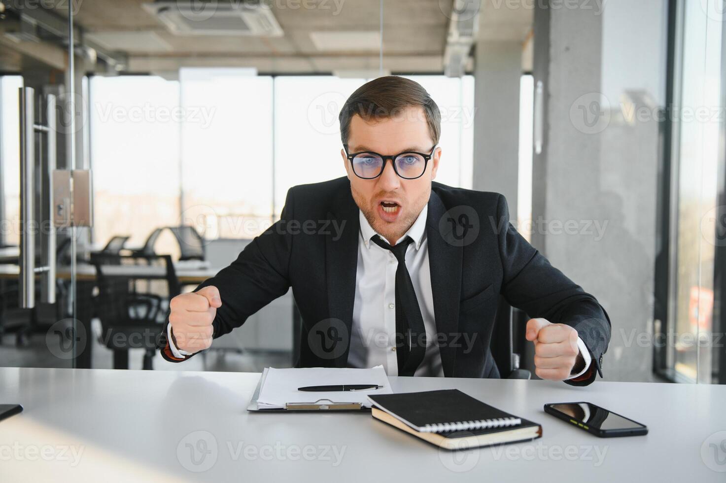 Angry businessman sitting at his desk and screaming at his employees. photo
