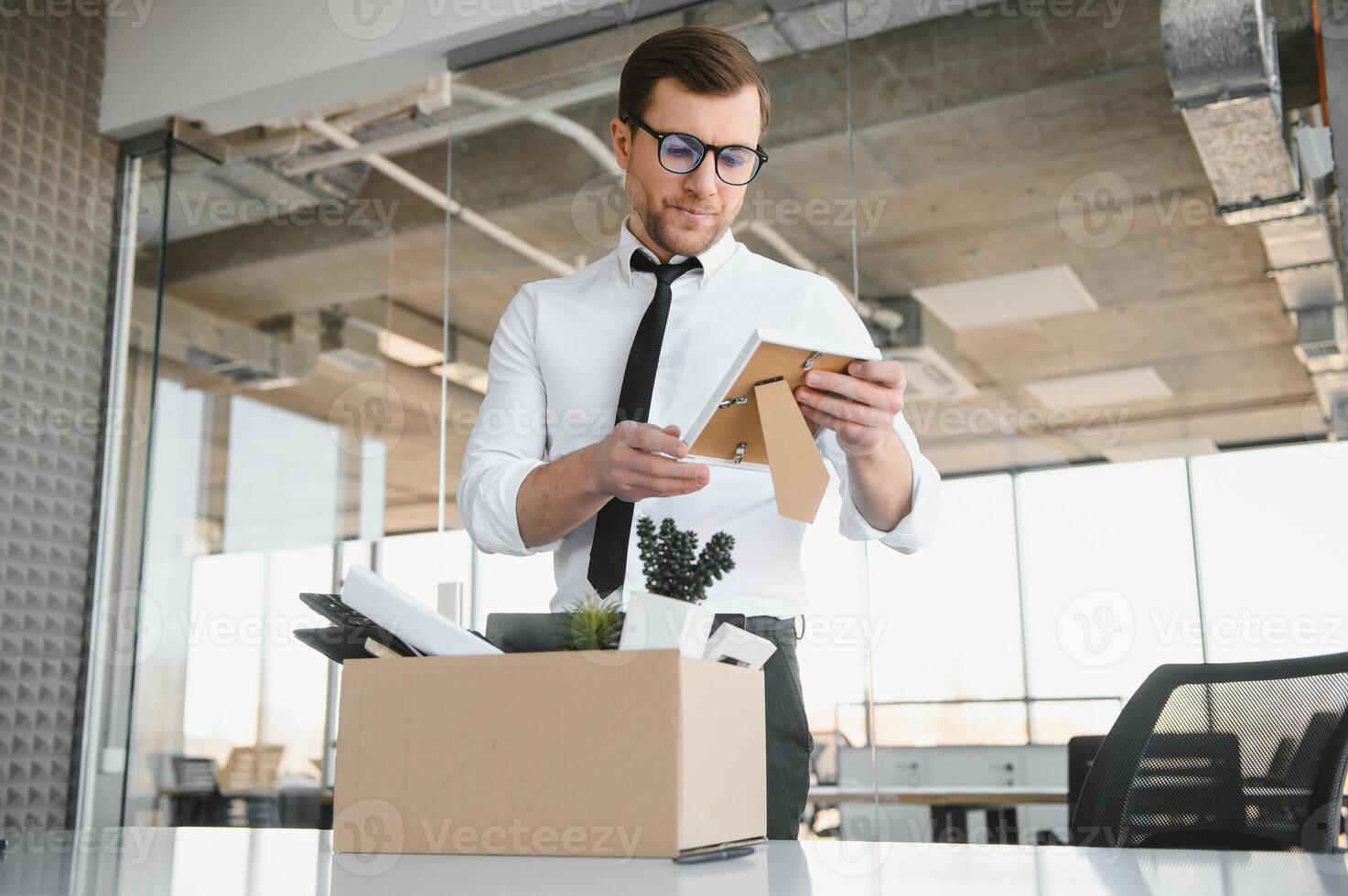 Fired young man packing his stuff in office photo