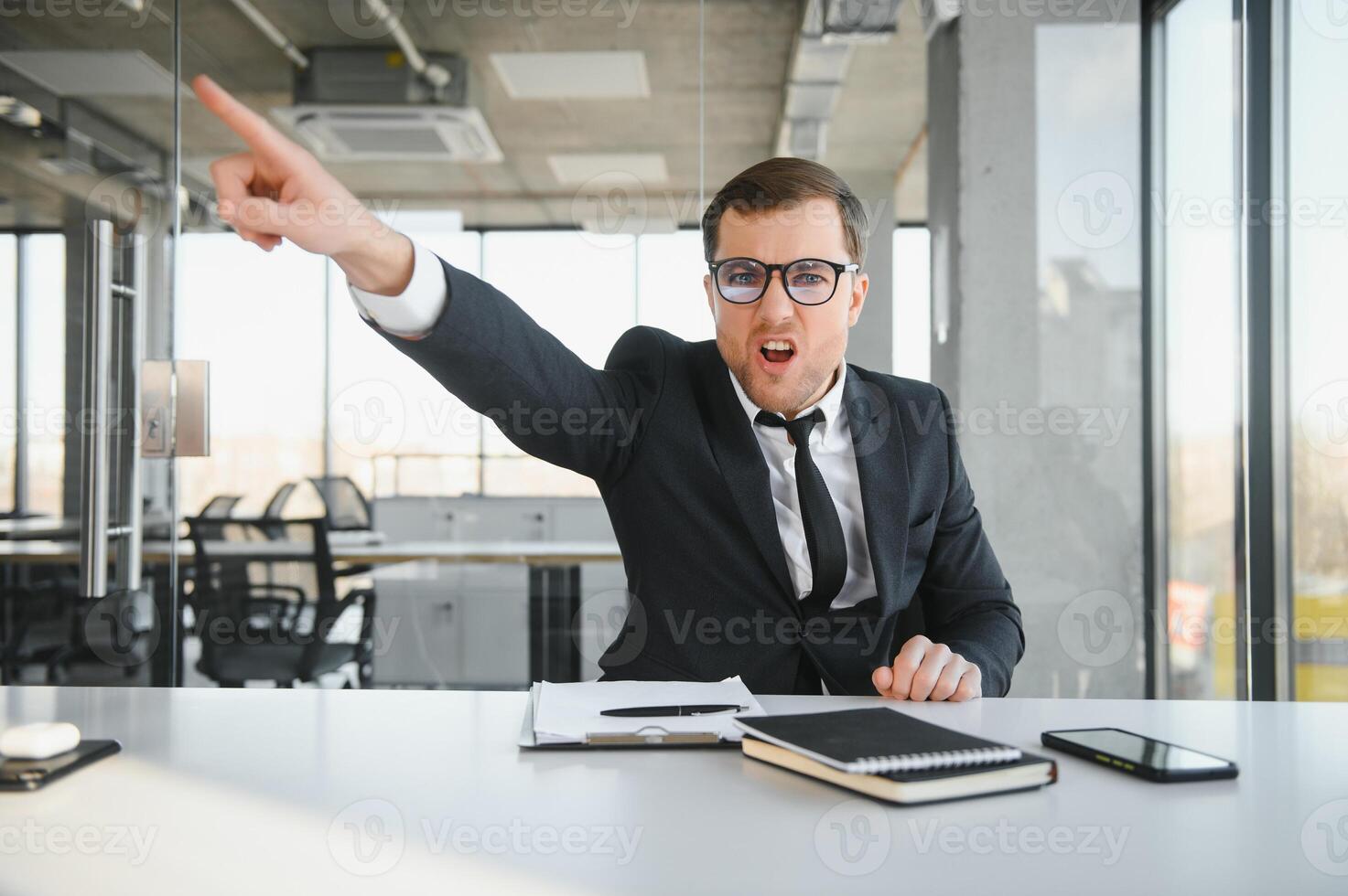 Angry senior businessman sitting at his desk and screaming photo
