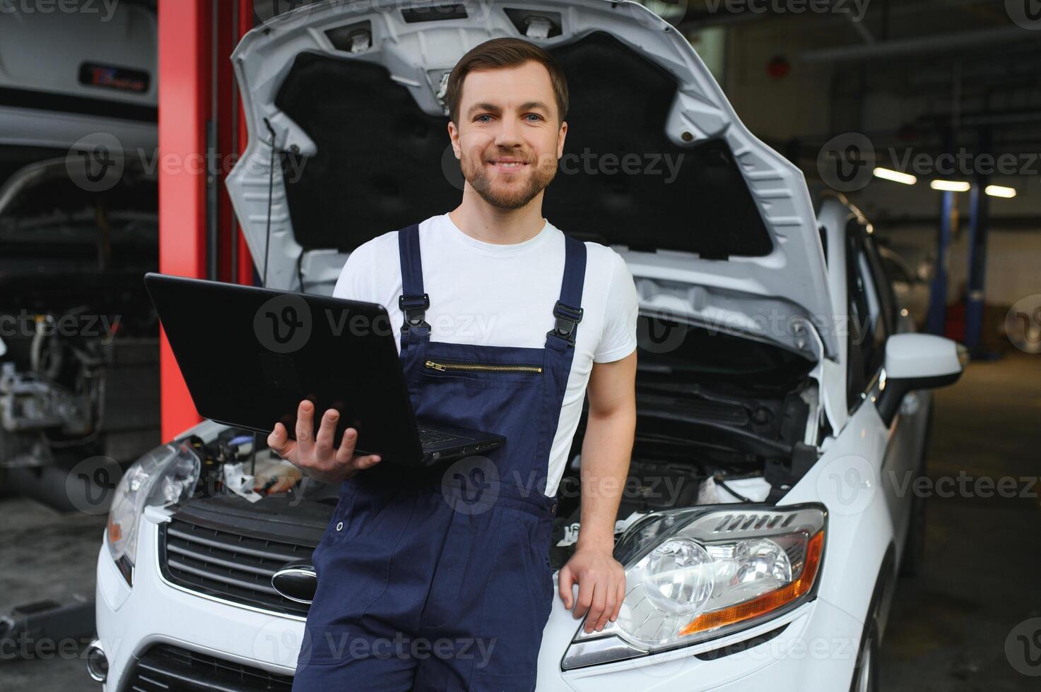 Mechanic man mechanic manager worker using a laptop computer checking car in workshop at auto car repair service center. Engineer young man looking at inspection vehicle details under car hood photo