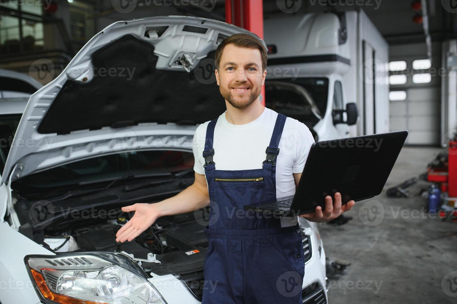With laptop. Adult man in uniform works in the automobile salon. photo