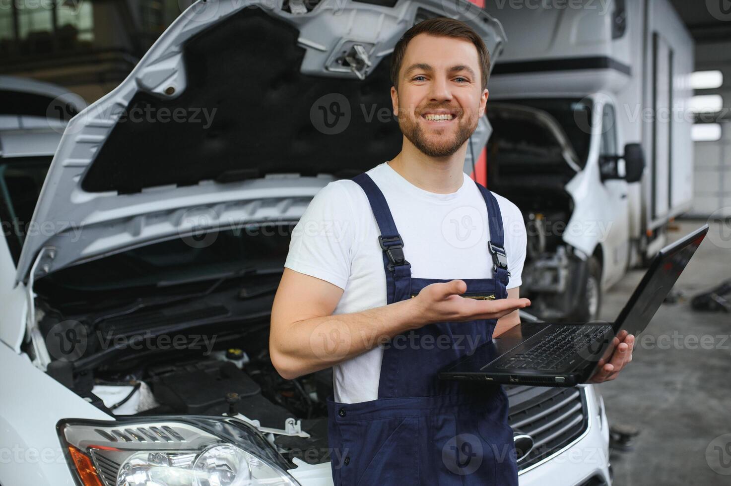 With laptop. Adult man in uniform works in the automobile salon. photo