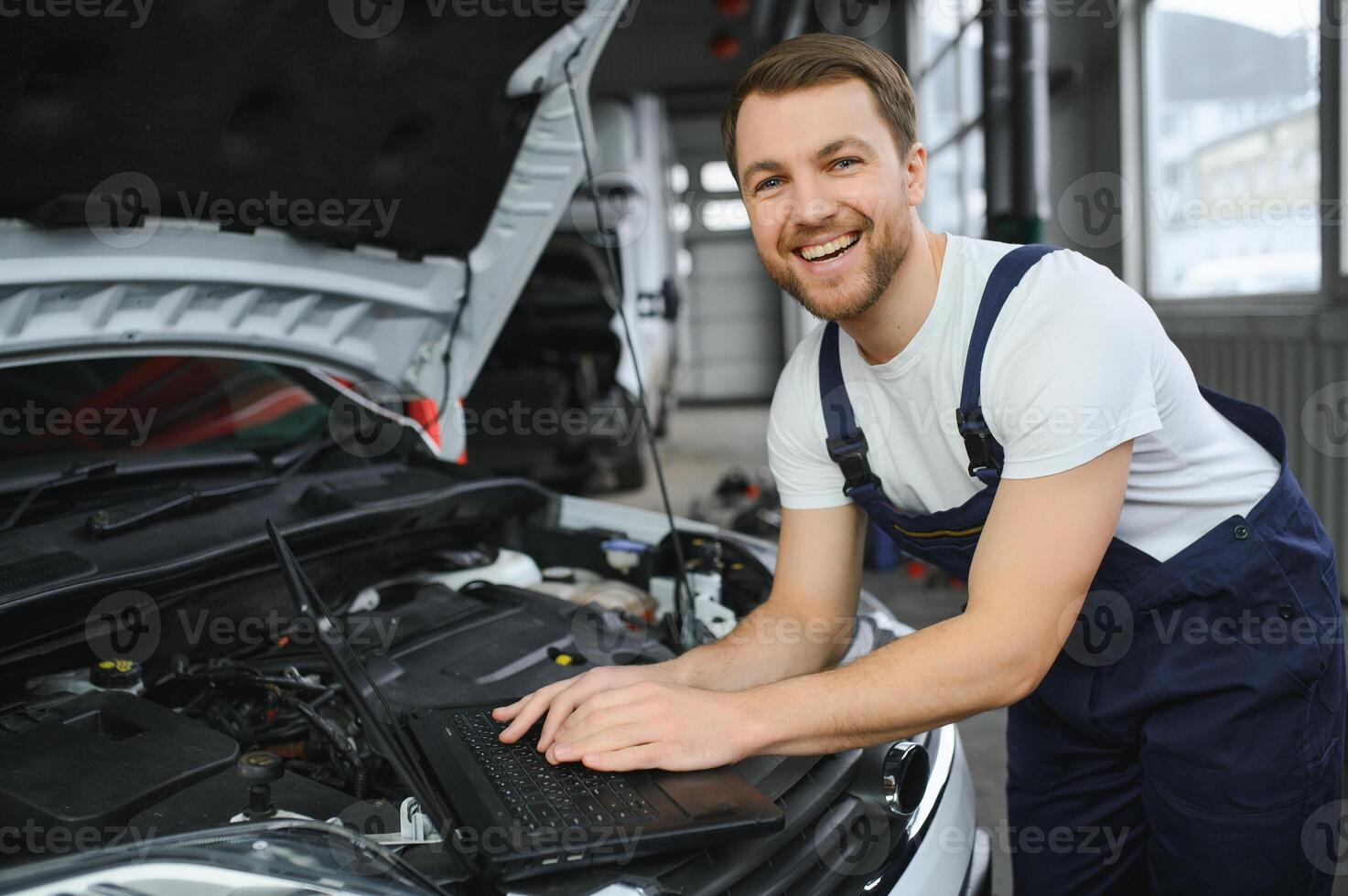 car mechanic using a computer laptop to diagnosing and checking up on car engines parts for fixing and repair photo