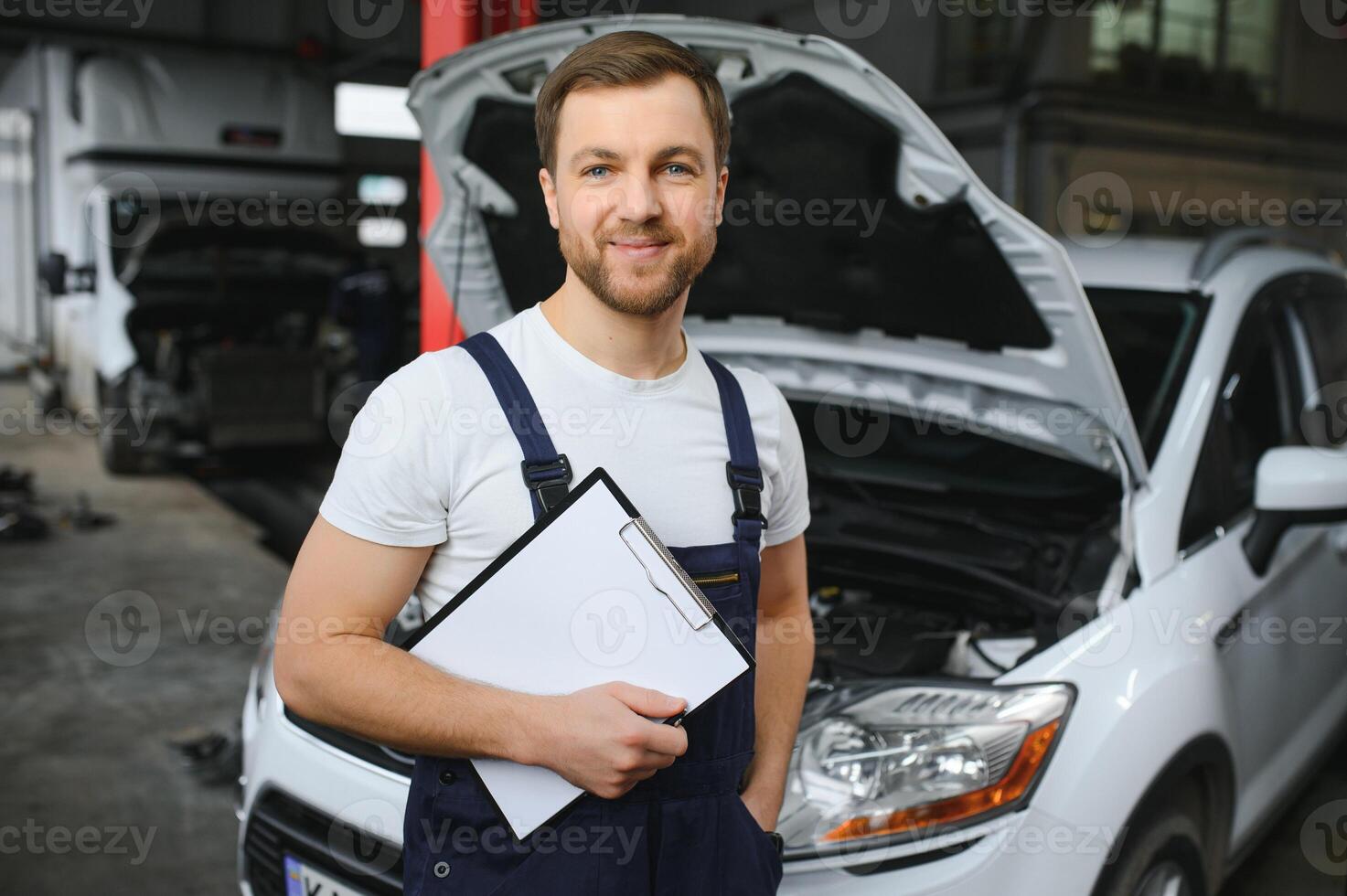 car service, repair, maintenance and people concept - happy smiling auto mechanic man or smith with clipboard at workshop photo