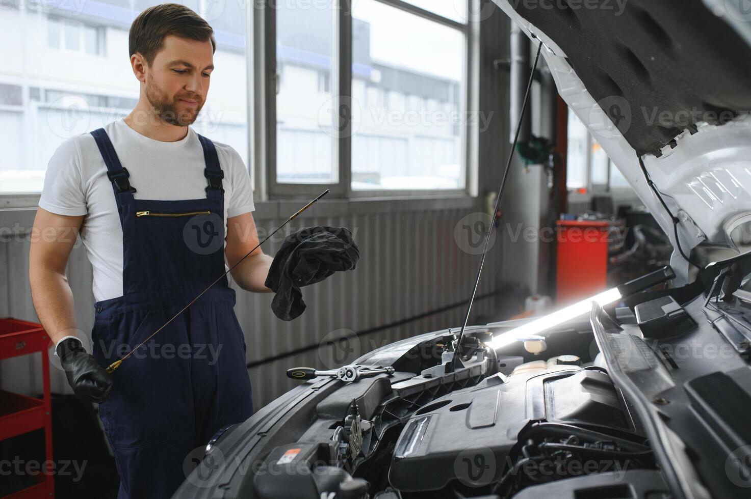 Auto mechanic checking the oil level in car engine,inspects engine water level dipstick,concept of checking the engine oil level every time before leaving. photo