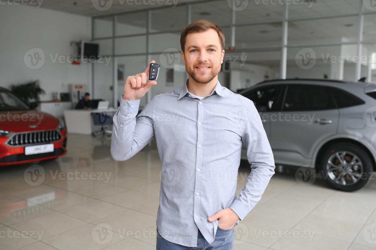 Yes, that's my new car. Customer in car dealership. Young man with keys in hand. photo