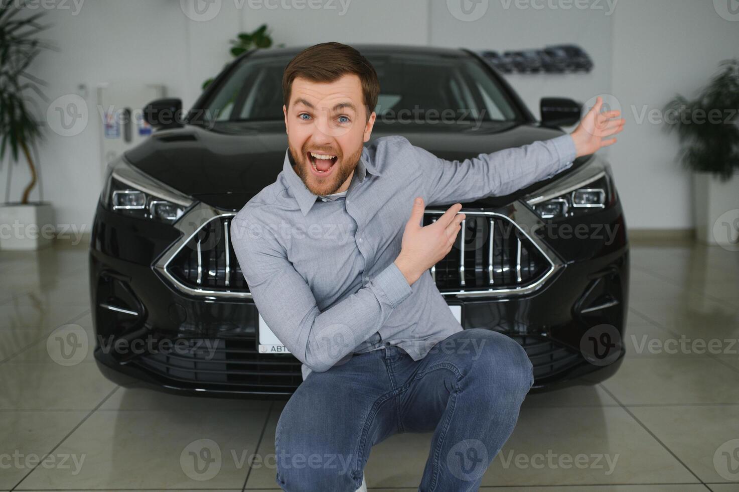 Visiting car dealership. Handsome bearded man is stroking his new car and smiling photo