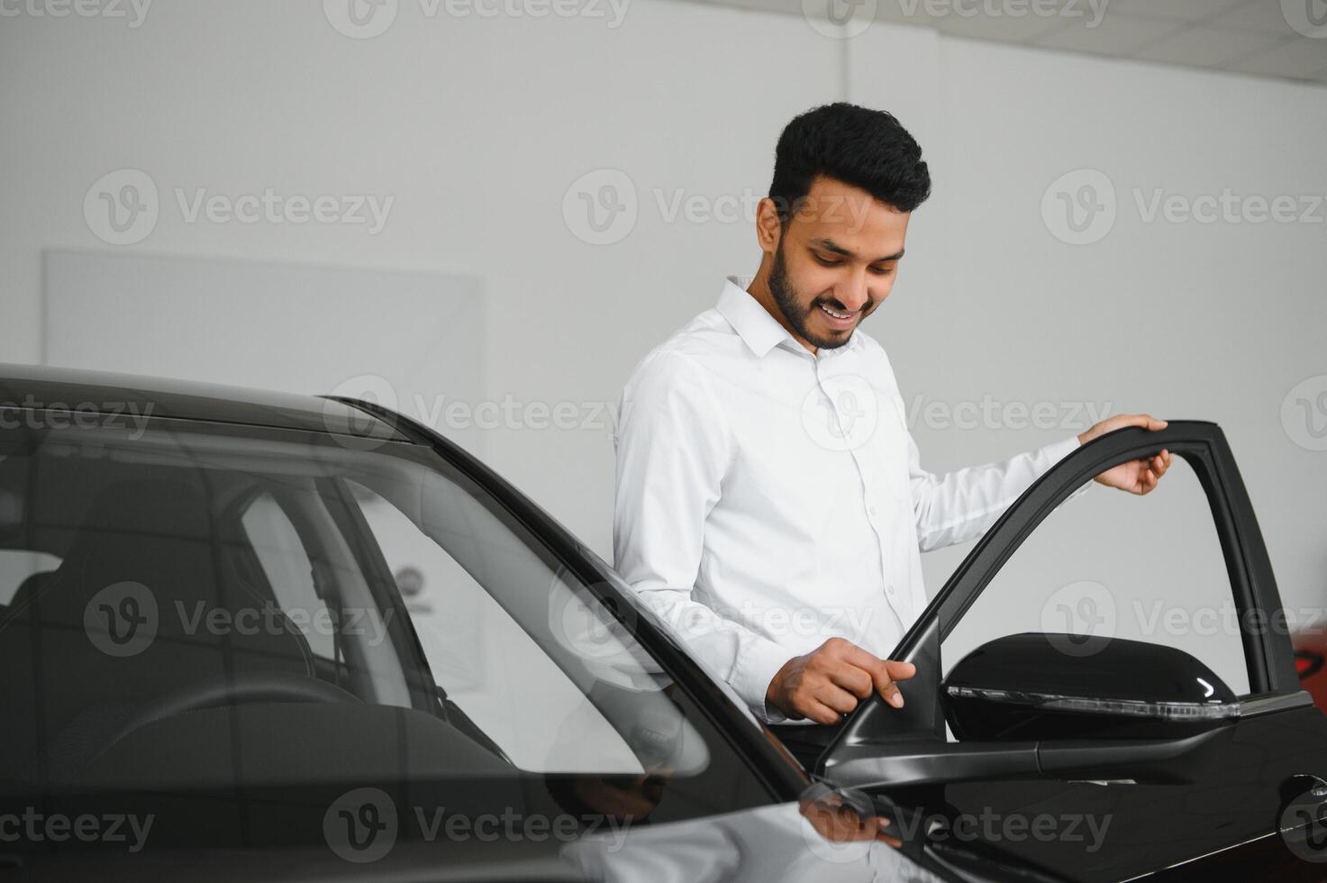 happy indian man checking car features at showroom photo