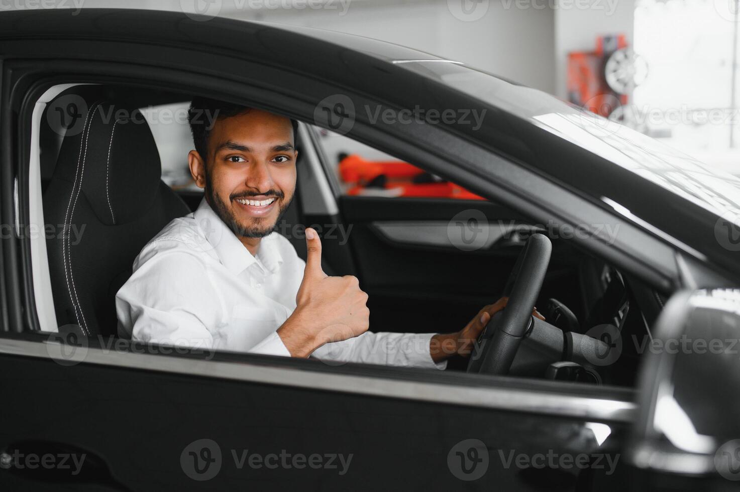 Young man sitting inside new car. Smiling photo