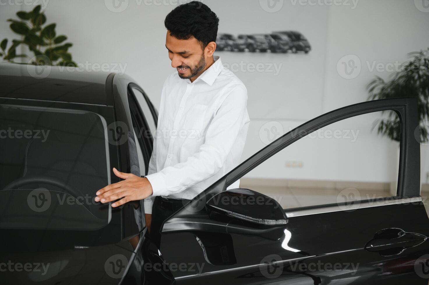 happy indian man buy new biodiesel eco automobile in lux showroom. photo