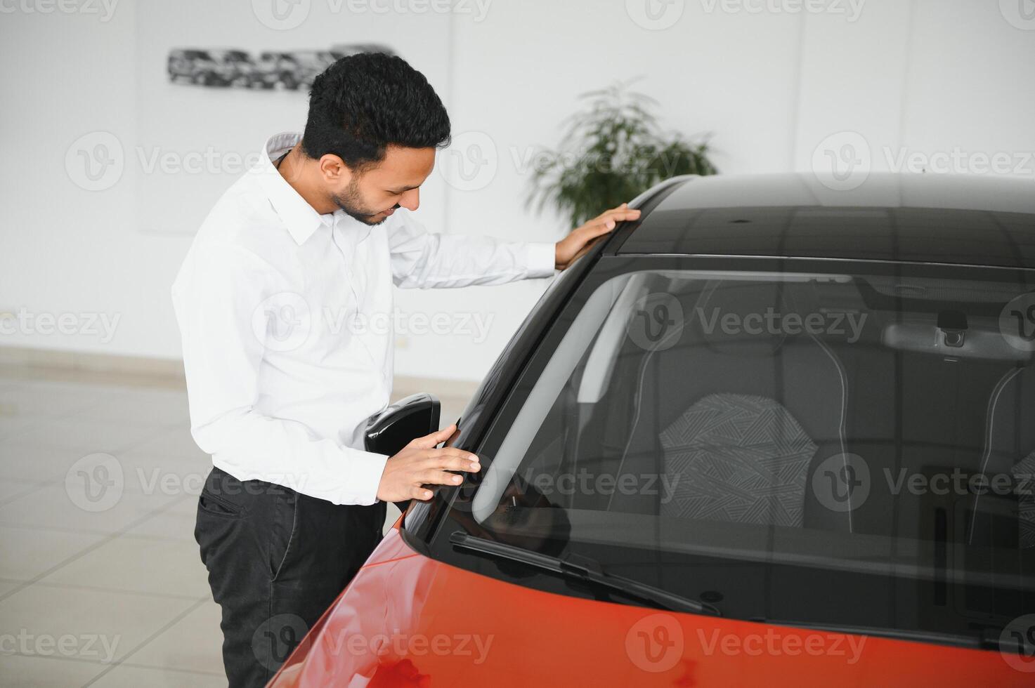 A young Indian man chooses a new car at a car dealership photo