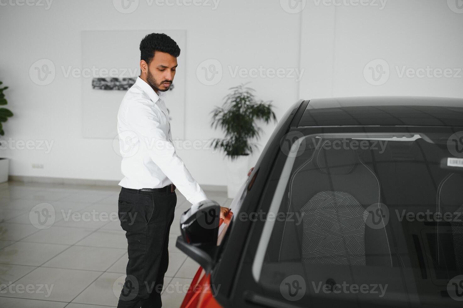 happy indian man checking car features at showroom photo